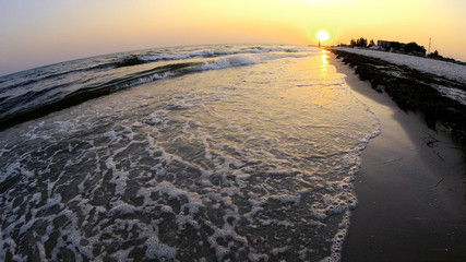 Amazing view of sea waves on the beach at sunset. Sand in sunset light. Vacation at resort.