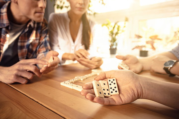 Two couples are playing dominoes while sitting in the the living room near the window.