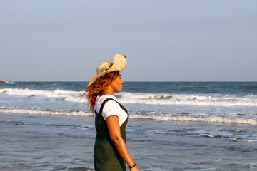 A young African lady in a sun hat playing by the beach