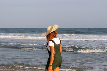 A young African lady in a sun hat playing by the beach