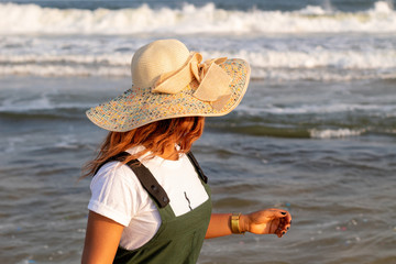A young African lady in a sun hat playing by the beach