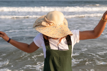 A young African lady in a sun hat playing by the beach