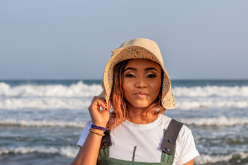 Portrait of a young African lady wearing a sun hat at the beach