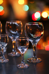 Empty glass transparent wine glasses on a table and colorful lights on a blurry dark background. Shallow focus.