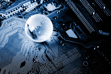 blue crystal globe sparkling on computer circuit board in the dark.