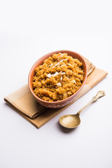 Wheat Laapsi/Lapsi/Shira/Halwa is an Indian sweet dish made of broken wheat or Daliya pieces and ghee along with nuts, raisins and dried fruits. It's a healthy food. served in a bowl, selective focus