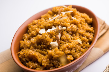 Wheat Laapsi/Lapsi/Shira/Halwa is an Indian sweet dish made of broken wheat or Daliya pieces and ghee along with nuts, raisins and dried fruits. It's a healthy food. served in a bowl, selective focus