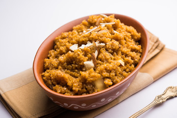 Wheat Laapsi/Lapsi/Shira/Halwa is an Indian sweet dish made of broken wheat or Daliya pieces and ghee along with nuts, raisins and dried fruits. It's a healthy food. served in a bowl, selective focus