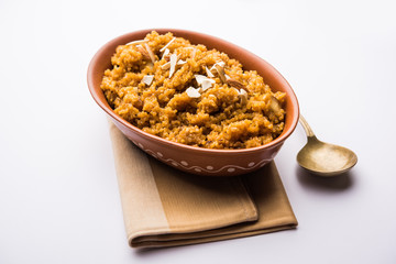Wheat Laapsi/Lapsi/Shira/Halwa is an Indian sweet dish made of broken wheat or Daliya pieces and ghee along with nuts, raisins and dried fruits. It's a healthy food. served in a bowl, selective focus