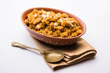 Wheat Laapsi/Lapsi/Shira/Halwa is an Indian sweet dish made of broken wheat or Daliya pieces and ghee along with nuts, raisins and dried fruits. It's a healthy food. served in a bowl, selective focus