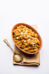 Wheat Laapsi/Lapsi/Shira/Halwa is an Indian sweet dish made of broken wheat or Daliya pieces and ghee along with nuts, raisins and dried fruits. It's a healthy food. served in a bowl, selective focus