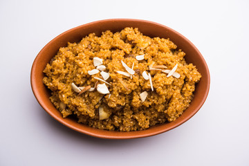 Wheat Laapsi/Lapsi/Shira/Halwa is an Indian sweet dish made of broken wheat or Daliya pieces and ghee along with nuts, raisins and dried fruits. It's a healthy food. served in a bowl, selective focus