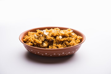 Wheat Laapsi/Lapsi/Shira/Halwa is an Indian sweet dish made of broken wheat or Daliya pieces and ghee along with nuts, raisins and dried fruits. It's a healthy food. served in a bowl, selective focus