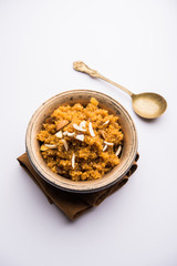 Wheat Laapsi/Lapsi/Shira/Halwa is an Indian sweet dish made of broken wheat or Daliya pieces and ghee along with nuts, raisins and dried fruits. It's a healthy food. served in a bowl, selective focus