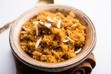 Wheat Laapsi/Lapsi/Shira/Halwa is an Indian sweet dish made of broken wheat or Daliya pieces and ghee along with nuts, raisins and dried fruits. It's a healthy food. served in a bowl, selective focus
