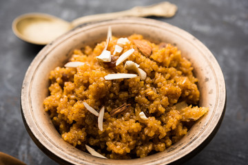 Wheat Laapsi/Lapsi/Shira/Halwa is an Indian sweet dish made of broken wheat or Daliya pieces and ghee along with nuts, raisins and dried fruits. It's a healthy food. served in a bowl, selective focus