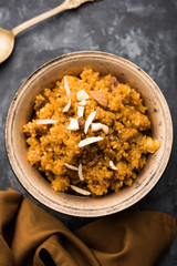 Wheat Laapsi/Lapsi/Shira/Halwa is an Indian sweet dish made of broken wheat or Daliya pieces and ghee along with nuts, raisins and dried fruits. It's a healthy food. served in a bowl, selective focus