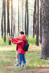 Couple asian traveler with backpack adventure holding map to find directions. People friend walking relax in jungle forest outdoor for destination leisure education nature in vacation. Travel Concept