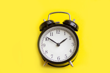Black alarm clock on yellow background