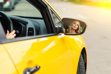 Photo of female driver reflecting back in yellow taxi mirror.