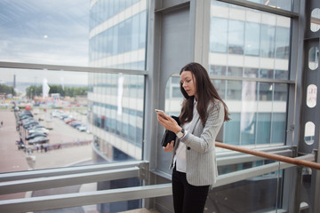 Young businesswoman with glasses and a phone in her hands. In the office or business center.