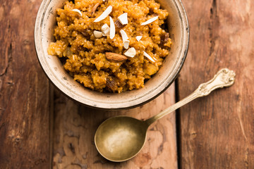 Wheat Laapsi/Lapsi/Shira/Halwa is an Indian sweet dish made of broken wheat or Daliya pieces and ghee along with nuts, raisins and dried fruits. It's a healthy food. served in a bowl, selective focus