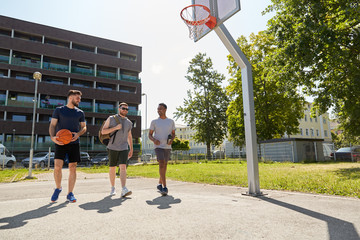 Fototapeta premium sport, leisure games and male friendship concept - group of men or friends going to play basketball outdoors