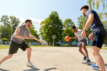 sport, leisure games and male friendship concept - group of men or friends playing street basketball