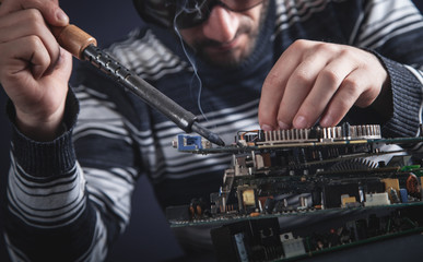 Computer hardware engineering. Engineer soldering computer motherboard