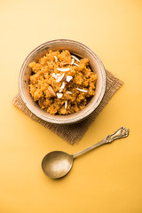 Wheat Laapsi/Lapsi/Shira/Halwa is an Indian sweet dish made of broken wheat or Daliya pieces and ghee along with nuts, raisins and dried fruits. It's a healthy food. served in a bowl, selective focus
