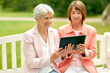 technology, old age and people concept - senior women with tablet pc computer at summer park