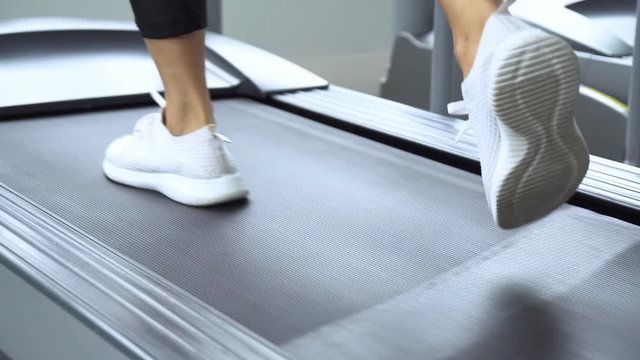 young sports woman running on treadmill in gym