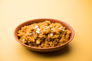 Wheat Laapsi/Lapsi/Shira/Halwa is an Indian sweet dish made of broken wheat or Daliya pieces and ghee along with nuts, raisins and dried fruits. It's a healthy food. served in a bowl, selective focus