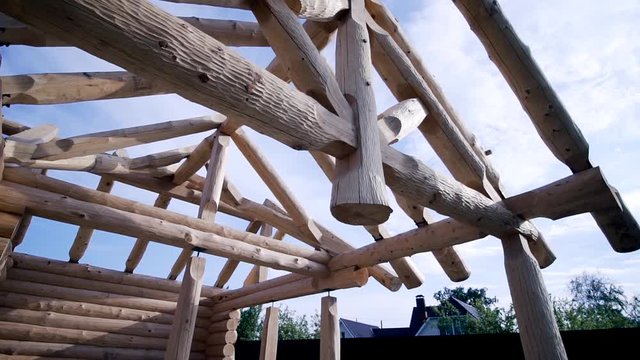 Frame of wooden country house under construction from logs. Clip. Construction of log house in beginning of construction on background of blue sky