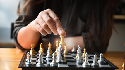 Cropped shot young woman paling chess board on table.