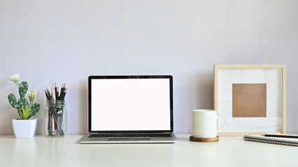 Workspace computer laptop, cactus, pencil, coffee and photo frame on table.