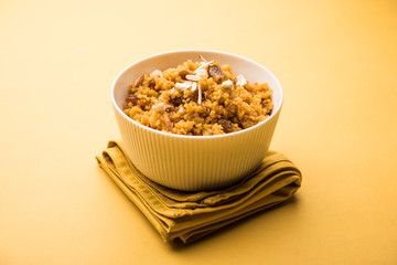 Wheat Laapsi/Lapsi/Shira/Halwa is an Indian sweet dish made of broken wheat or Daliya pieces and ghee along with nuts, raisins and dried fruits. It's a healthy food. served in a bowl, selective focus