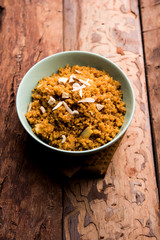 Wheat Laapsi/Lapsi/Shira/Halwa is an Indian sweet dish made of broken wheat or Daliya pieces and ghee along with nuts, raisins and dried fruits. It's a healthy food. served in a bowl, selective focus