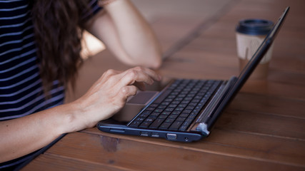 Neat young female hands with a modest manicure, with large wrist watches, work at a laptop,...