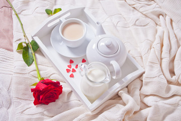 Close up of cup of tea with red rose on the white tray