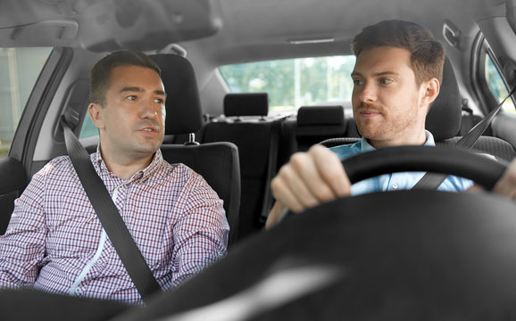 car driving lesson and carpooling concept - instructor on passenger seat and young driver talking