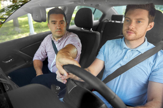 driver courses and people concept - car driving school instructor teaching young man to drive