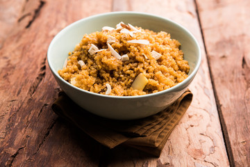 Wheat Laapsi/Lapsi/Shira/Halwa is an Indian sweet dish made of broken wheat or Daliya pieces and ghee along with nuts, raisins and dried fruits. It's a healthy food. served in a bowl, selective focus