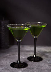 Two glasses with green zombie cocktail for Halloween party on the gray background