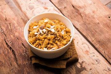 Wheat Laapsi/Lapsi/Shira/Halwa is an Indian sweet dish made of broken wheat or Daliya pieces and ghee along with nuts, raisins and dried fruits. It's a healthy food. served in a bowl, selective focus