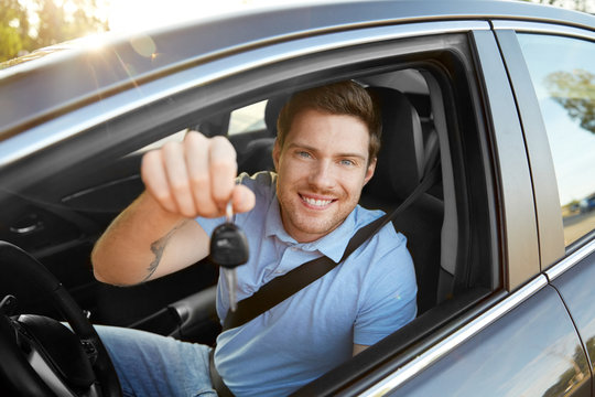 transport, vehicle and ownership concept - happy smiling man or driver with key sitting in car