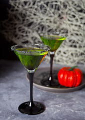 Two glasses with green zombie cocktail for Halloween party on the gray background