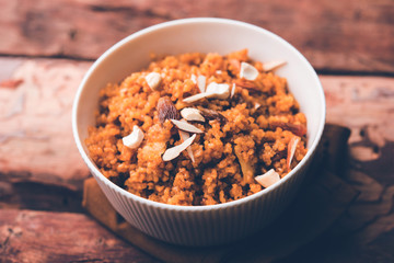 Wheat Laapsi/Lapsi/Shira/Halwa is an Indian sweet dish made of broken wheat or Daliya pieces and ghee along with nuts, raisins and dried fruits. It's a healthy food. served in a bowl, selective focus