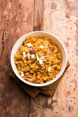 Wheat Laapsi/Lapsi/Shira/Halwa is an Indian sweet dish made of broken wheat or Daliya pieces and ghee along with nuts, raisins and dried fruits. It's a healthy food. served in a bowl, selective focus