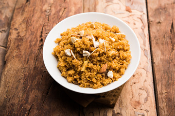 Wheat Laapsi/Lapsi/Shira/Halwa is an Indian sweet dish made of broken wheat or Daliya pieces and ghee along with nuts, raisins and dried fruits. It's a healthy food. served in a bowl, selective focus
